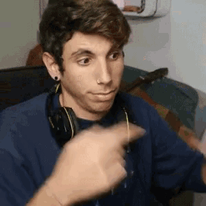 a young man wearing headphones is pointing at something