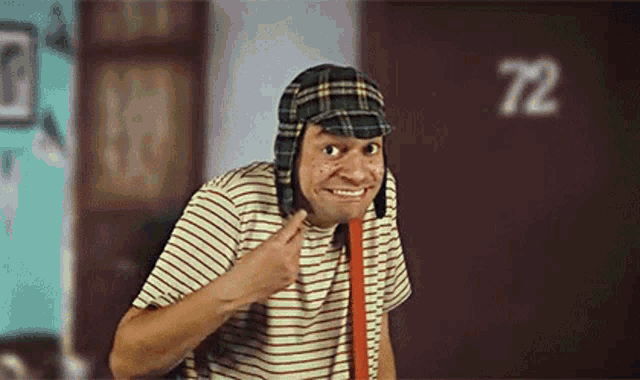 a man wearing a plaid hat and a striped shirt is making a funny face .