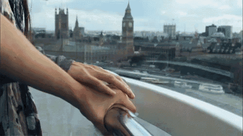 a woman 's hand rests on a railing overlooking the city of london
