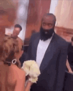 a man in a suit and tie is standing next to a bride holding a bouquet of flowers .