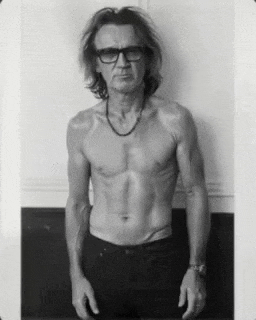 a black and white photo of a shirtless man wearing glasses