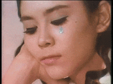 a close up of a woman 's face with a tear running down her cheek