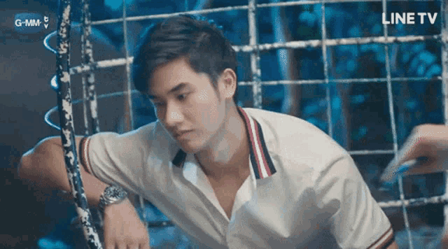 a man in a white shirt is leaning against a fence with a line tv logo in the corner