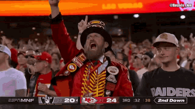a crowd of people watching a raiders game with a man wearing a top hat