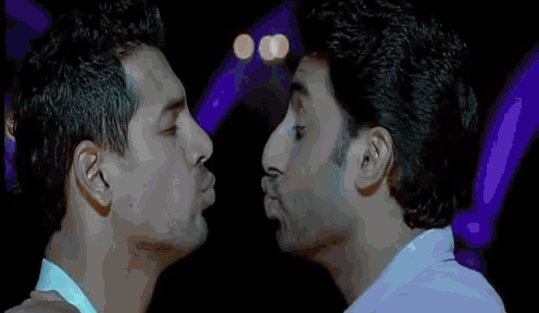 two men are kissing each other with purple lights in the background