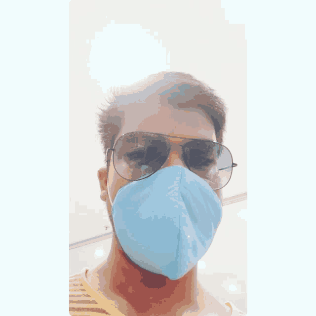 a man wearing sunglasses and a blue mask looks at the camera