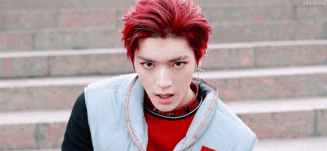 a young man with red hair is wearing a red sweater and a gray vest .