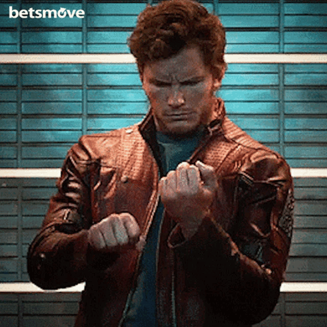 a man in a leather jacket is standing in front of a brick wall with the words betsmove on the bottom