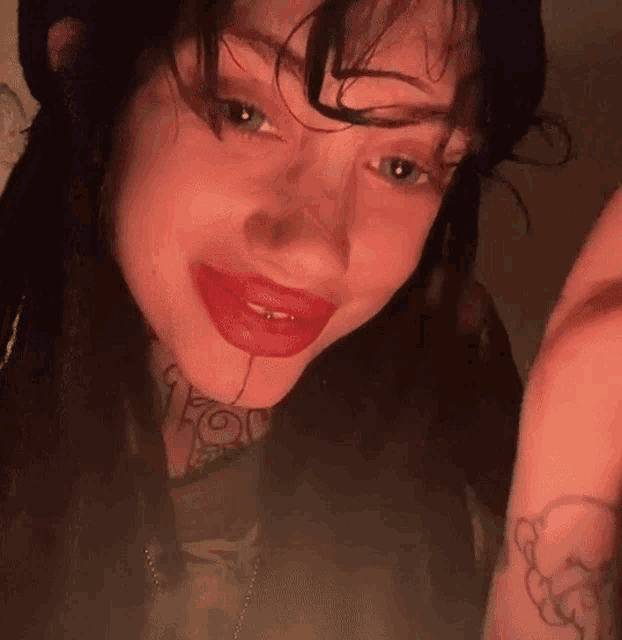 a close up of a woman with red lipstick and a tattoo on her neck .