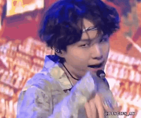 a young man is singing into a microphone while wearing a headband .