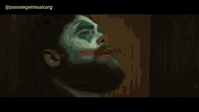 a man with a beard is dressed as a clown with a red nose .