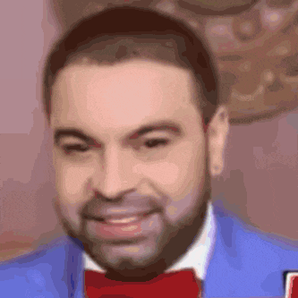 a man with a beard wearing a blue suit and a red bow tie