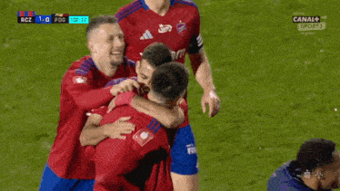 a group of soccer players are hugging and celebrating a goal