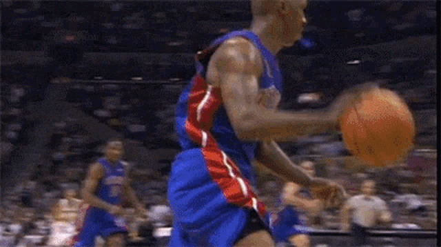 a basketball player in a blue red and white uniform dribbles the ball