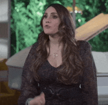 a woman in a black dress is standing in front of a piano and looking at the camera .