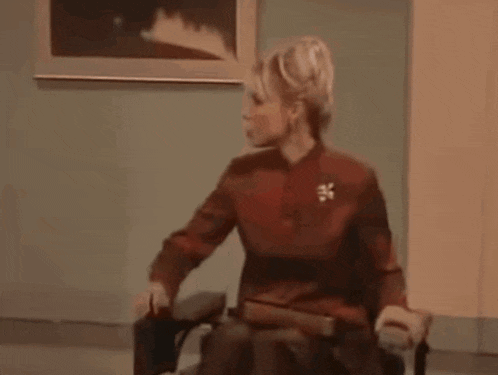 a woman is sitting in a chair in a room with a picture on the wall .