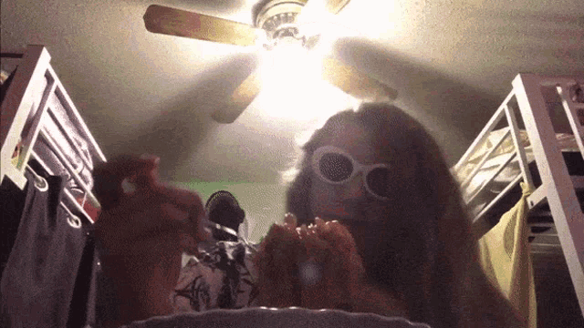 a person wearing sunglasses is sitting in a closet with a ceiling fan