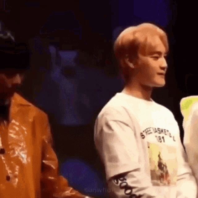 a man in a white shirt is standing next to another man in a yellow jacket .