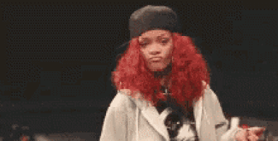 a woman with red hair is wearing a hat and making a peace sign with her hands .