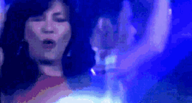 a woman is singing into a microphone in front of a blue background .