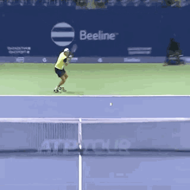 a tennis player is swinging a racket on a court with an advertisement for beeline
