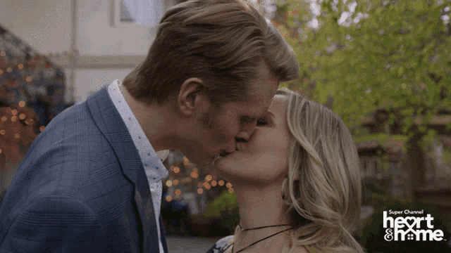 a man and woman kiss in front of a super channel heart & home logo