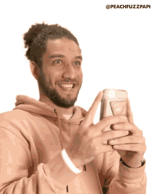 a man in a pink hoodie is holding a cell phone in his hand