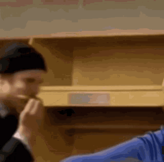 a man in a black hat is eating something in a locker room .