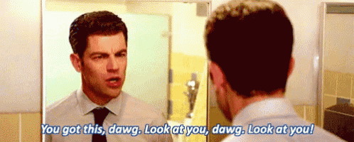 a man in a suit and tie is looking at himself in a mirror .