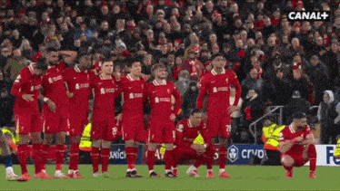 a group of soccer players kneeling on the field with canal + in the corner