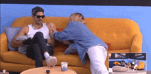 a man and a woman are sitting on a yellow couch and talking to each other .
