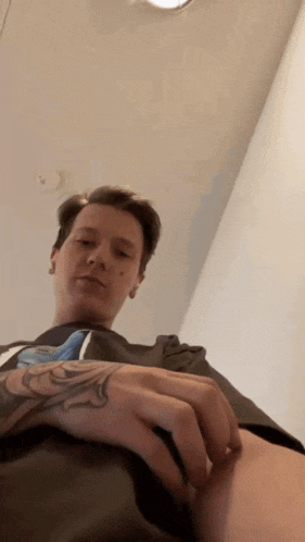 a man with a tattoo on his arm is sitting in a chair and looking at the camera .
