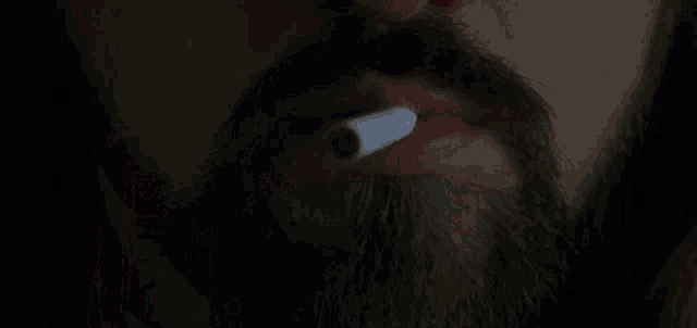 a man is lighting a cigarette with a box of nails cigarettes in the background