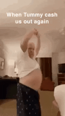 a man with a very large belly is dancing in a living room with his arms in the air .