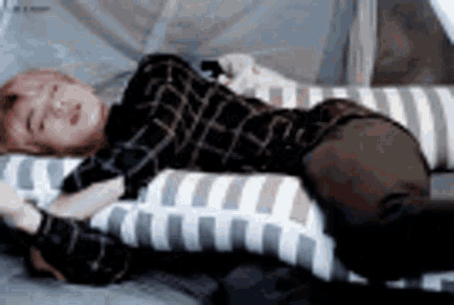 a person is laying on a couch with a pillow on their stomach .