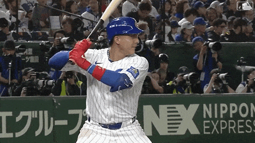 a baseball player swings at a ball in front of a banner for nippon express
