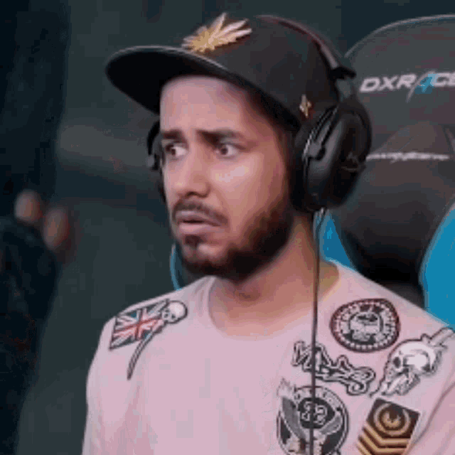 a man wearing headphones and a hat is sitting in a chair that says dxr