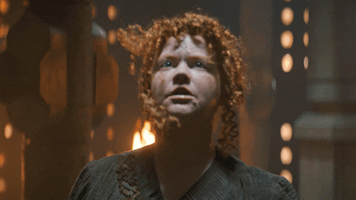 a woman with red curly hair is looking up at the sky