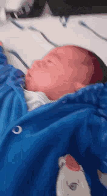 a baby is wrapped in a blue blanket with a teddy bear on it