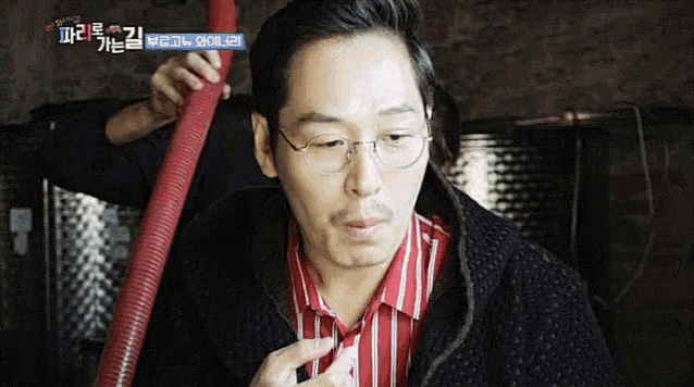 a man wearing glasses and a red and white striped shirt holds a red hose in his hand