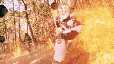a man in a white suit is surrounded by flames in the woods