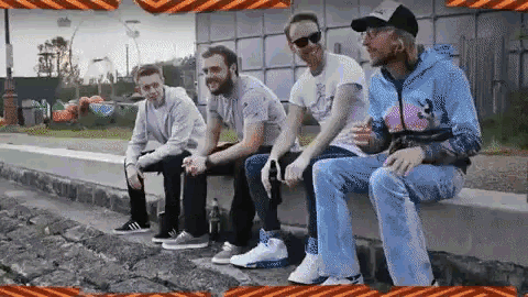 a group of men are sitting on a ledge with a sign that says no smoking