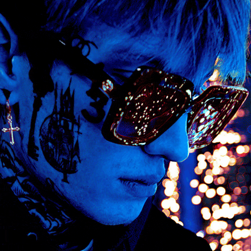 a close up of a person wearing sunglasses with a cross earring