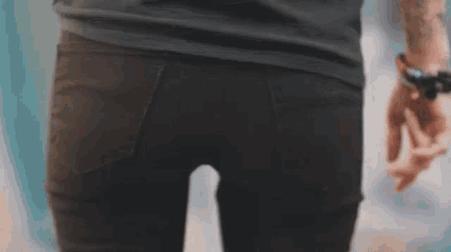 a close up of a person 's butt in black jeans and a watch on their wrist .