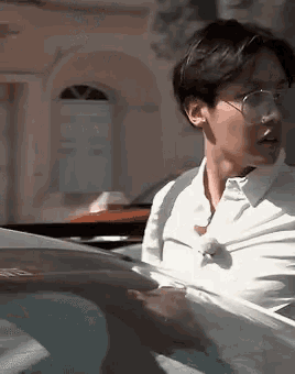 a man wearing glasses and a white shirt is sitting in a car .