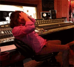 a woman in a pink shirt sits in a recording studio with her hands on her head