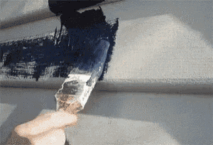 a person is holding a brush and painting a wall with black paint
