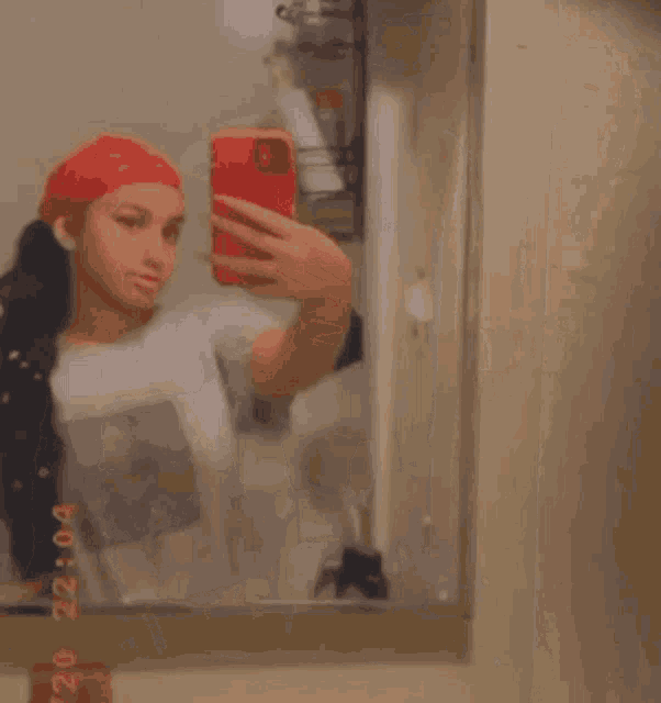 a woman is taking a selfie in a bathroom mirror .
