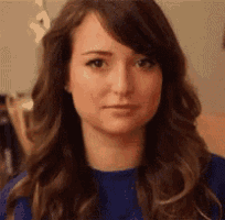 a woman with long hair is wearing a blue sweater and making a face .