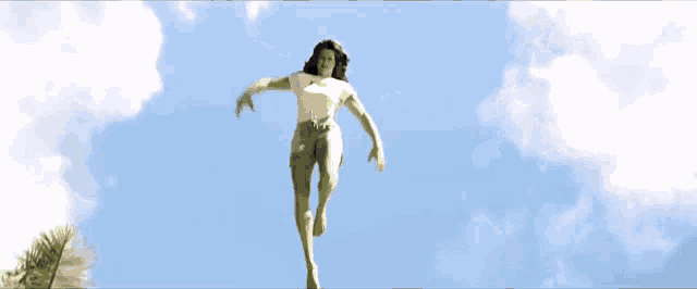 a woman in a white shirt and green shorts is kicking up her leg in the air